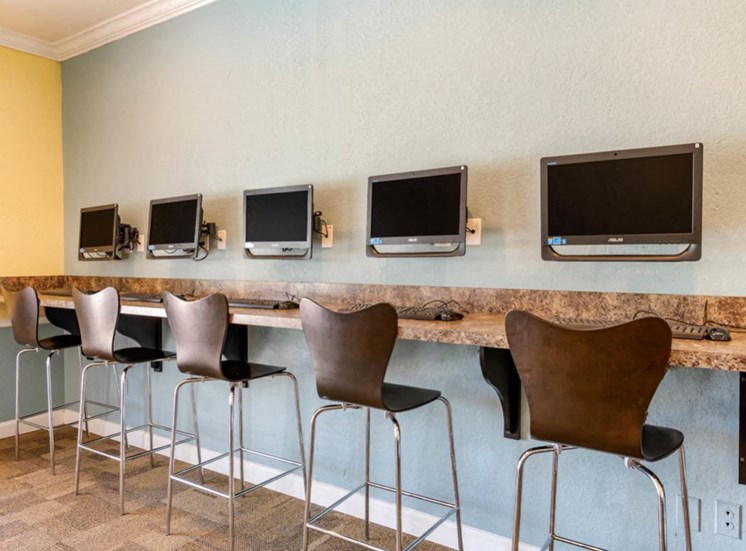 Resident Business Center with Computers Mounted to the Wall Above Bar with Brown Bar Stools
